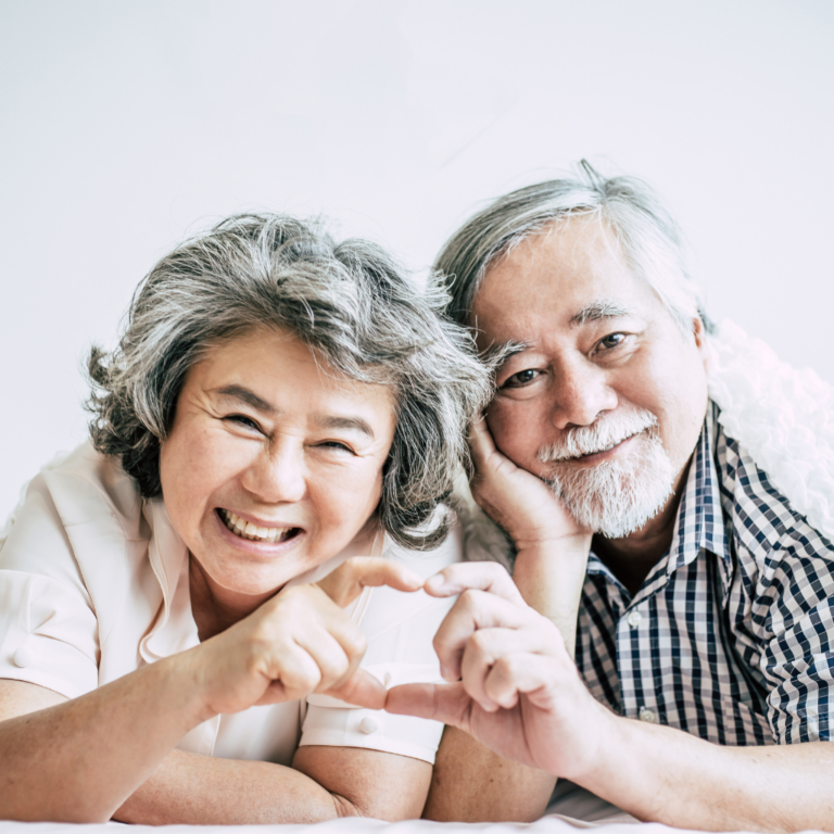 Happy elderly couple making a heart sign with hands showing love, affection and gratitude.